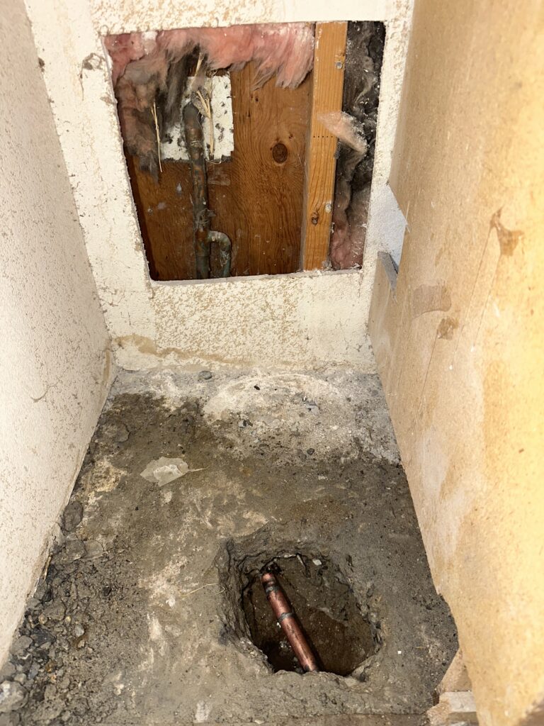 Water leaking from plumbing pipe beneath concrete slab foundation inside residential home