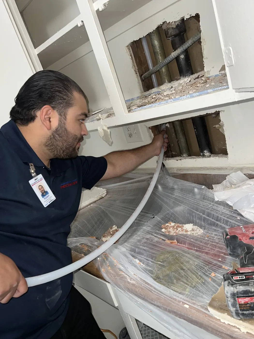 Technician routing a new water pipe through open kitchen walls