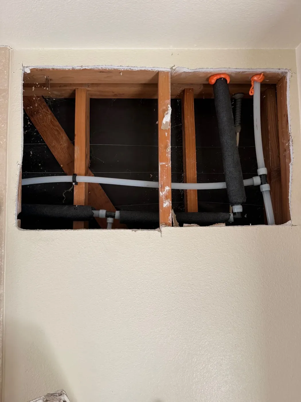 Hot and cold water lines visible inside an open wall