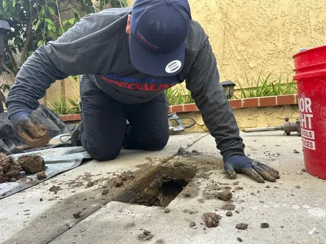 Technician excavating beside a residential walkway
